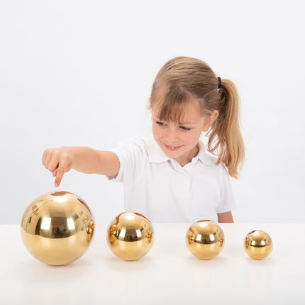 meisje speelt met Tickit 4 sensorische goudkleurige ballen