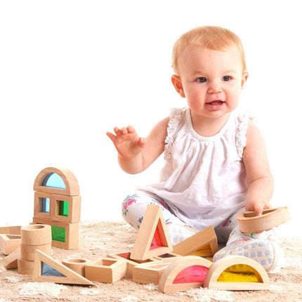 baby speelt met houten regenboogblokken