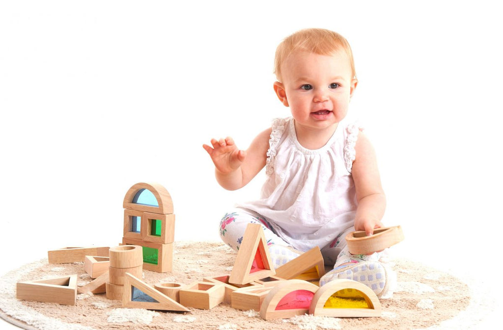 baby speelt met houten regenboogblokken