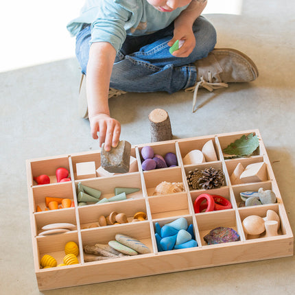 kind speelt met gevulde houten sorteerbak of tinker tray van grapat